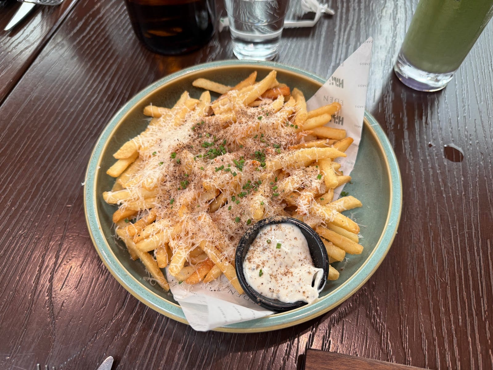 Eden's Truffle Fries topped with grated cheese and chives, with a pot of truffle mayo