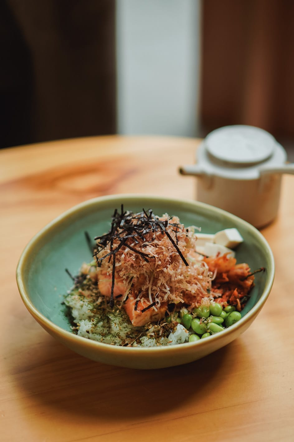 Salmon Chazuke: rice topped with salmon, bonito flakes, nori and edamame, with a teapot behind